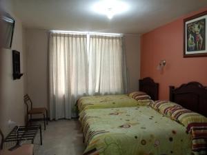1 dormitorio con 2 camas y una ventana con cortinas en Hostal EL CALLEJÓN, en Ibarra