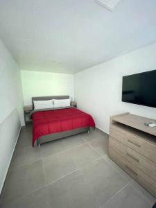a bedroom with a red bed and a flat screen tv at 304A-APARTA ESTUDIO DUPLEX MINI EN Granada in Cali