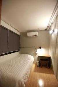 Habitación pequeña con cama y escritorio. en My Home Hostel, en Ban Na Kham