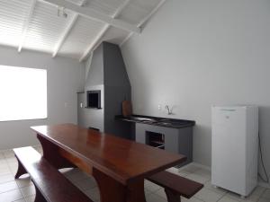 a kitchen with a wooden table and a refrigerator at Casa Ampla no Centro, Piso Térreo ou Superior in Bombinhas