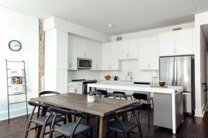 a kitchen with white cabinets and a wooden table and chairs at Roami at The Luzianne in New Orleans