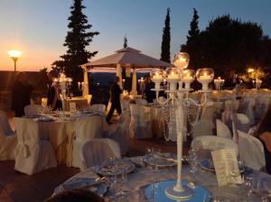 un grupo de mesas con sillas blancas y velas en Hotel Pomara, en San Michele di Ganzaria