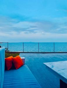 a blue bench with orange pillows next to the ocean at Villa Palma in Alexandroupoli