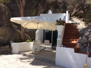 une maison blanche avec un parasol, des chaises et des escaliers dans l'établissement Urlaub im kleinen Bergparadies, à Las Casillas