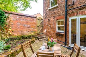 a patio with a wooden table and two benches at Fisherman's Cottage in Chester