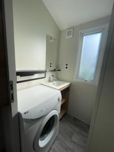 a bathroom with a washing machine and a sink at Mobilhome Salsa XXL in Gastes