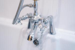a bathroom sink with aaucet with a clock on it at Fisherman's Cottage in Chester +23 photos