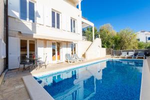 a swimming pool in front of a white house at vila ivan i ian in Stanići