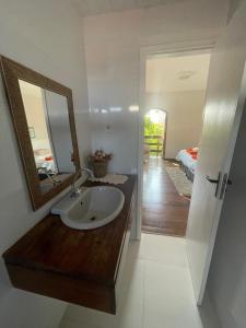 a bathroom with a sink and a mirror and a bedroom at Enjoy Hostel e Pousada in Aracaju