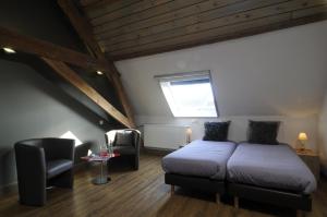 a bedroom with a bed and a chair and a window at Oud Gemeentehuis in Poelkapelle