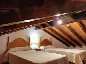 two beds in a room with wooden ceilings at Apartamentos rurales La Casa Vieja De Alceda in Alceda