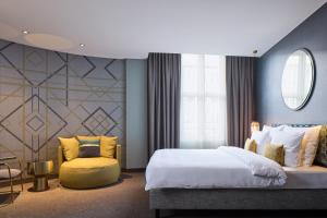 a bedroom with a large bed and a yellow chair at Postboutique Hotel Wuppertal in Wuppertal