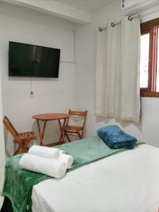 Habitación con cama, mesa y TV. en Espaço da Mélia, en Gramado