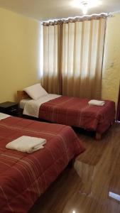 a hotel room with two beds with red sheets at Las Palmeras Eco Hostel in Cabanaconde