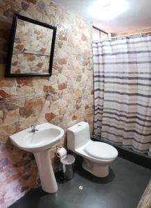a bathroom with a white toilet and a sink at Las Palmeras Eco Hostel in Cabanaconde
