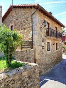 un edificio de piedra con balcón. en Apartamentos rurales La Casa Vieja De Alceda en Alceda