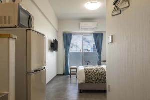 um quarto de hotel com uma cama e uma janela em Mr.KINJO in Miegusuku em Naha