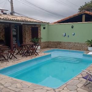 une grande piscine bleue avec des chaises et une table dans l'établissement Recanto da Iara, à Arraial do Cabo
