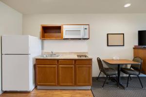 a kitchen with a white refrigerator and a table at WoodSpring Suites Fredericksburg in Fredericksburg