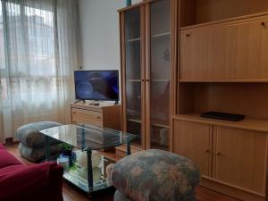 sala de estar con mesa de cristal y TV en Apartamentos Virita Coqueto Apartamento vacacional, próximo a la playa, en A Coruña