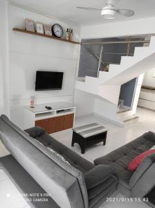 a living room with a couch and a tv at Confortável Duplex a 100 Metros da Praia in Porto Seguro