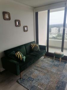 a living room with a green couch and a large window at Reñaca - Eluchans Plaza in Viña del Mar