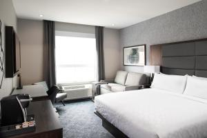 a hotel room with a large bed and a chair at Holiday Inn Express - Boston South - Quincy by IHG in Quincy +38 photos