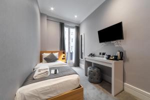 1 dormitorio con 1 cama y escritorio con TV en Gainsborough Hotel, en Londres