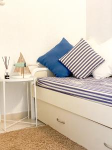 Una cama con almohadas azules y blancas y una mesa. en La Polena Camere Vernazza - Visconti Apartment, en Vernazza