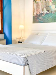 Una cama blanca en una habitación con una pintura en La Polena Camere Vernazza - Visconti Apartment, en Vernazza