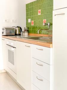 a kitchen with white cabinets and green tiles at La Polena Camere Vernazza - Visconti Apartment in Vernazza