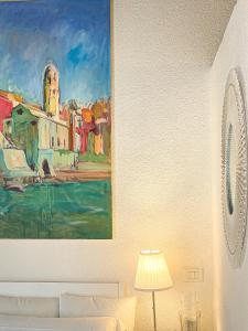 a painting hanging on a wall next to a bed at La Polena Camere Vernazza - Visconti Apartment in Vernazza