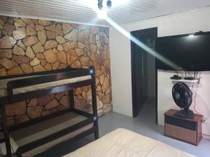 Cette chambre dispose de lits superposés et d'un mur en pierre. dans l'établissement Recanto da Iara, à Arraial do Cabo