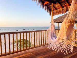 a hammock on a deck overlooking the ocean at Vila Beijú BARRINHA - Frente Mar! in Barrinha