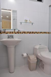 Baño blanco con lavabo y aseo en Hotel B`Quin Plaza Cúcuta, en Cúcuta