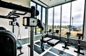 a gym with a row of tread machines and windows at Hotel Das Zeit in Lenzing