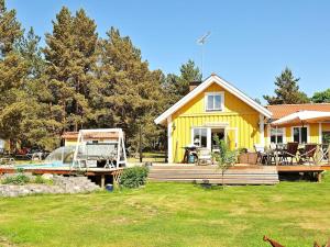 a yellow house with a boat in front of it at Two-Bedroom Holiday home in Blidö 1 in Finnholmen