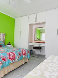a bedroom with a bed and a desk with a mirror at Direct Access to the Beach in Port Edward