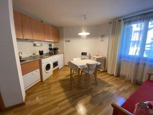 - une cuisine avec une table et une table et des chaises blanches dans l'établissement Apartamento Formigal - Sallent de Gállego, à Sallent de Gállego