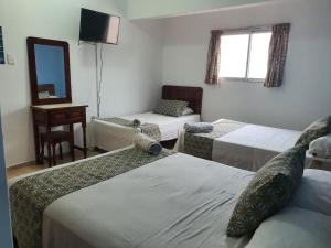 a hotel room with three beds and a mirror at Hotel El Faro Malecon in Veracruz