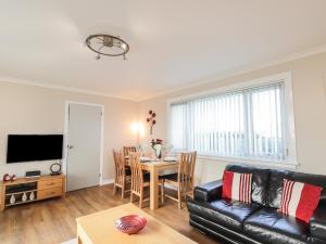 a living room with a black leather couch and a table at Rose Cottage in Lybster