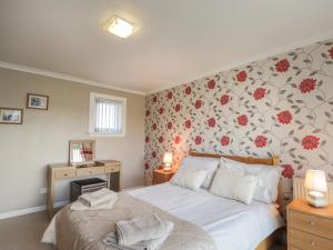 a bedroom with a bed with a floral wallpaper at Rose Cottage in Lybster