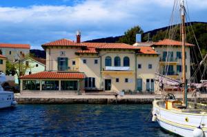 a small boat docked in front of a large house at Hotel Televrin in Nerezine