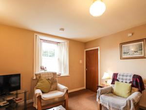 a living room with two chairs and a television at Granny's Cottage in Dunbeath