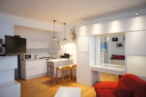 uma cozinha e sala de estar com armários brancos e um sofá vermelho em Apartments Berlaymont OHY em Bruxelas