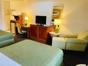Habitación de hotel con 2 camas, escritorio y TV. en Red Carpet Inn Duncannon, en New Buffalo