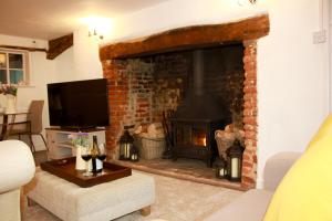 a living room with a fireplace and a tv at Romantic* Castle on the Hill Cottage *Framlingham in Framlingham