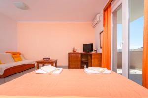 a bedroom with two beds and a tv and a balcony at Rosić Apartments in Tivat