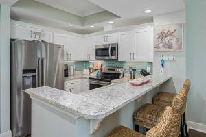 een keuken met witte kasten en een granieten aanrecht bij Crystal Shores III in Gulf Shores