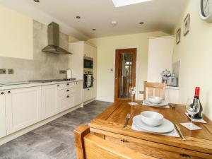 a kitchen with white cabinets and a wooden table at Decca Cottage Nidd Grange in York